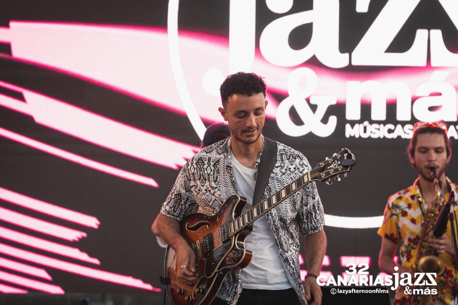 Lucas Baret playing at Canarias Jazz & Más, a saxophonist beside him and the festival screen behind